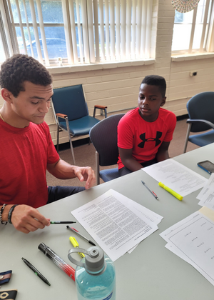 Photo of Grind Out student tutor Noah Miller helping a young male student with Algebra