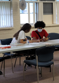 Female Grind out student tutor helping a young male student study